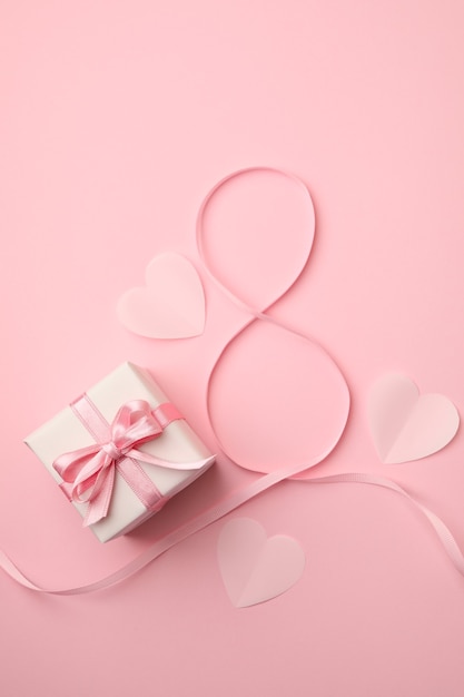 8 de cinta, corazones y caja de regalo sobre fondo rosa