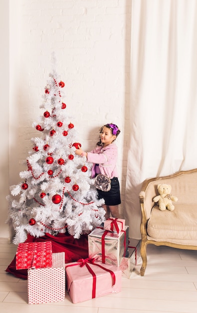 8 Jahre altes kleines Mädchen, das Weihnachtsbaum zu Hause verziert.