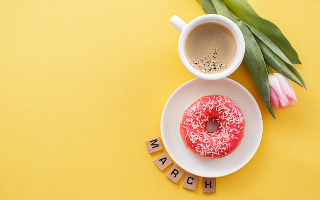 8 de marzo Día Internacional de la Mujer número ocho compuesto por una taza de café y un donut con cobertura rosa junto a tulipanes rosas espacio para texto