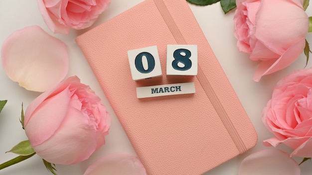 8 de marzo día de la mujer en el diario rosa decorado con flores rosas sobre fondo blanco de mesa