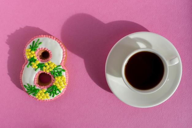 8 de marzo pastel y taza de café sobre un fondo rosa brillante