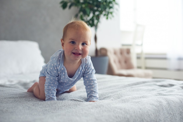 8 meses de idade menino feliz rastejando na cama em casa