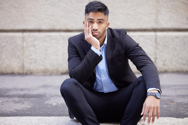 Esto de 9-5 realmente me está afectando. Una foto de un apuesto joven hombre de negocios sentado y aburrido en la ciudad.