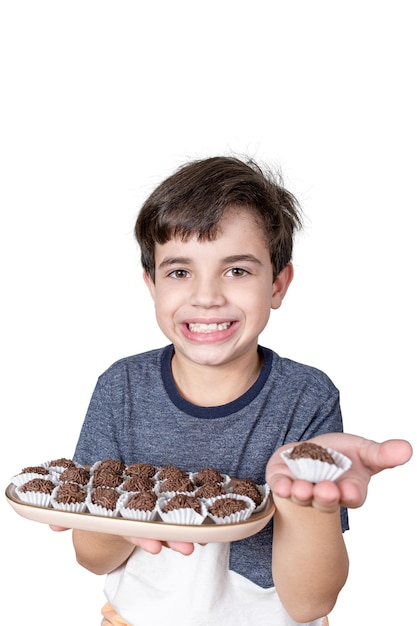 9-jähriger Brasilianer hält ein Tablett mit mehreren brasilianischen Fudgebällchen und in der anderen Hand nur eine Süßigkeit