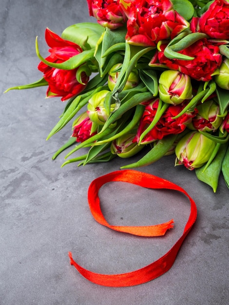 9 de mayo tulipanes rojos de fondo y cinta roja en el fondo de hormigón espacio libre para texto