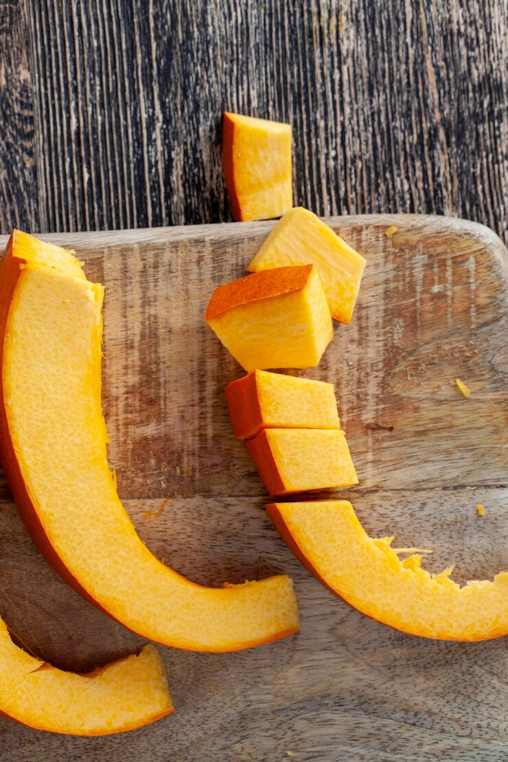 A abóbora laranja doce e madura é cortada sobre a mesa com partes de abóbora madura laranja