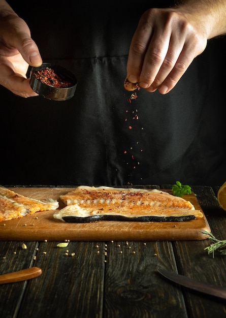 A adição de especiarias secas aos bifes de peixe para aroma e sabor da culinária americana O processo de preparação de peixe pelas mãos de um chef em um restaurante ou cozinha de hotel