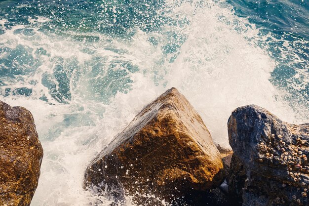 A água do mar bate contra rochas rochosas e faz ondas com espuma no cais acidentado no mar