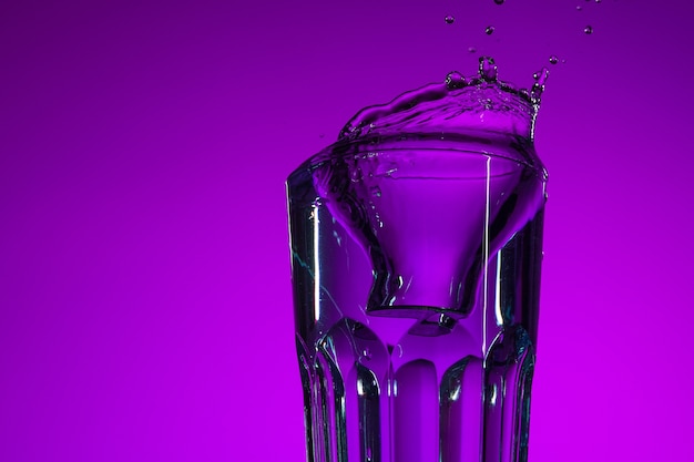 Foto a água espirrando em vidro sobre fundo lilás