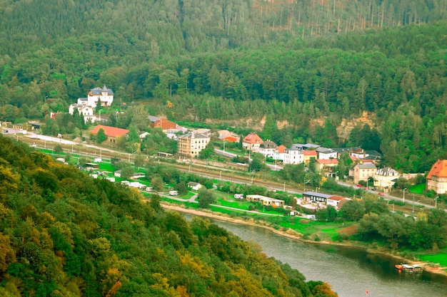 A aldeia com casas perto do rio e florestas verdes vista de cima