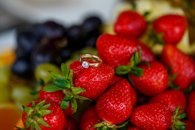 A aliança de casamento encontra-se em um morango vermelho maduro. Frutas deliciosas de verão