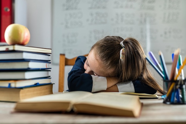 A aluna está dormindo na mesa da escola porque está cansada