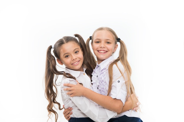 A amizade da escola é tão especial Adoráveis pequenos amigos abraçando isolados no branco Alunas felizes desfrutando da amizade Filhinhos comemorando o dia da amizade