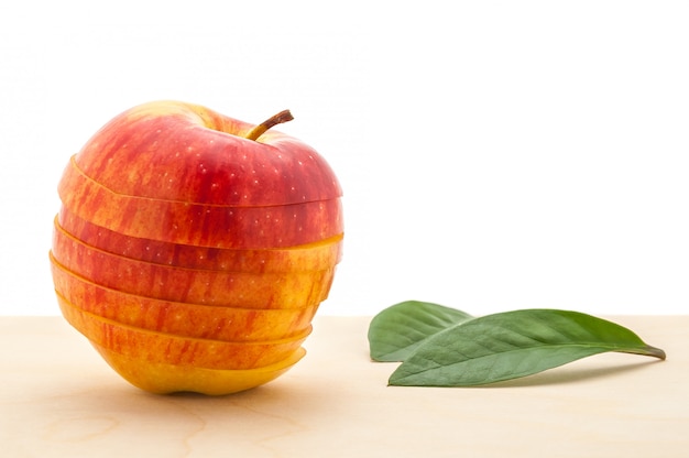 A Apple preservou sua forma, mas cortou em fatias e duas folhas em uma mesa de madeira.