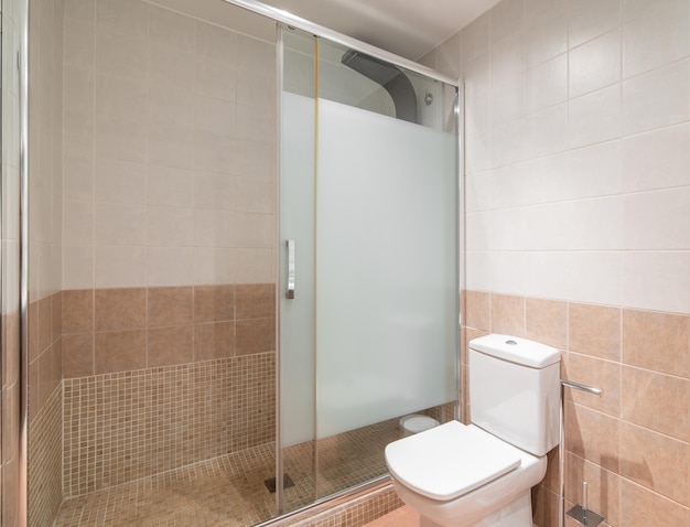 A área do chuveiro é separada do banheiro compartilhado por uma divisória deslizante feita de vidro fosco durável