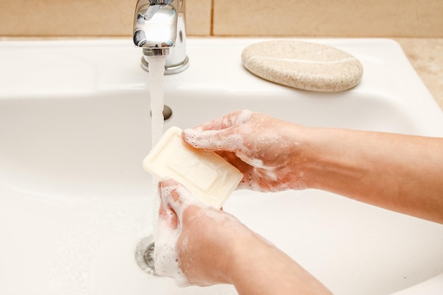 A As mãos com sabão são lavadas na torneira com água