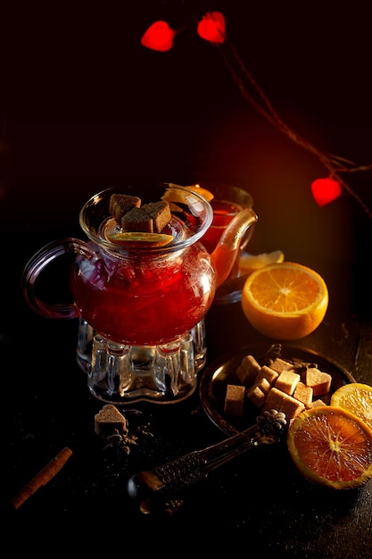 A atmosfera da atmosfera de ano novo Chaleira em suporte com velas aquecidas Em uma chaleira de vinho quente ou chá de hibisco com limão Paus de canela e laranja