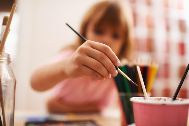 A aula de arte é a sua favorita Uma garotinha mergulhando o pincel na água