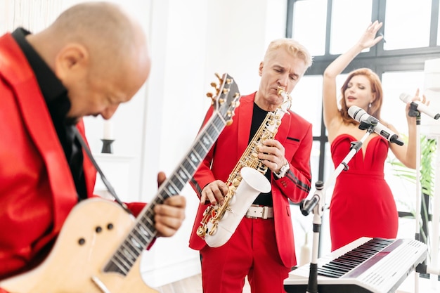 A banda cover toca instrumentos musicais saxofone microfone piano Um grupo de músicos canta