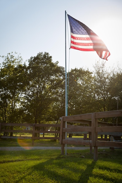 A bandeira americana está acenando no mastro no quintal da casa ao pôr do sol