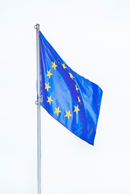 A bandeira da união europeia se desenvolve ao vento em um mastro de bandeira isolado em um fundo branco