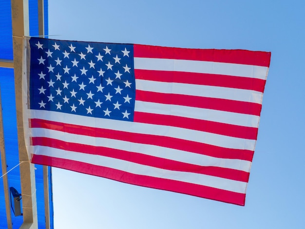 A bandeira dos Estados Unidos tremula em uma viga sob o telhado Bandeira sob a tendência do restaurante à beira-mar Bandeira estrelada contra o céu