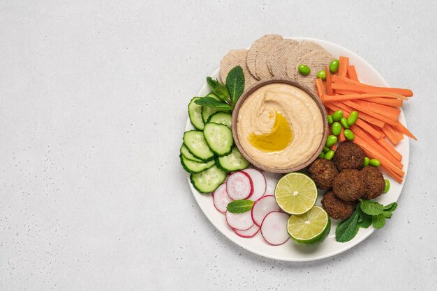 A bandeja é servida com molho de húmus, falafel, rabaneto, pepino, cenoura, cenouras, biscoitos.