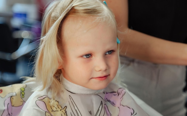 A barbeira faz um penteado bonito e elegante para uma linda garotinha loira