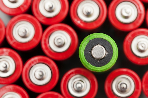 A bateria verde se destaca contra as baterias vermelhas Conceito de reciclagem e fornecimento de energia verde