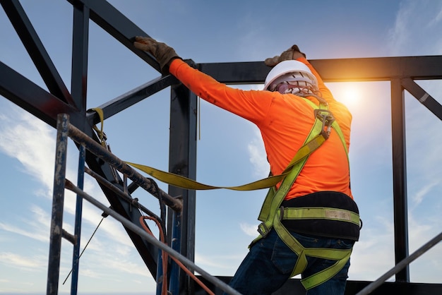 A Bauarbeiter tragen Sicherheitsausrüstung, um Stürze aus der Höhe zu verhindern, oder eine Fallschutzvorrichtung für Arbeiter mit Haken für Sicherheitsgurte auf der Baustelle