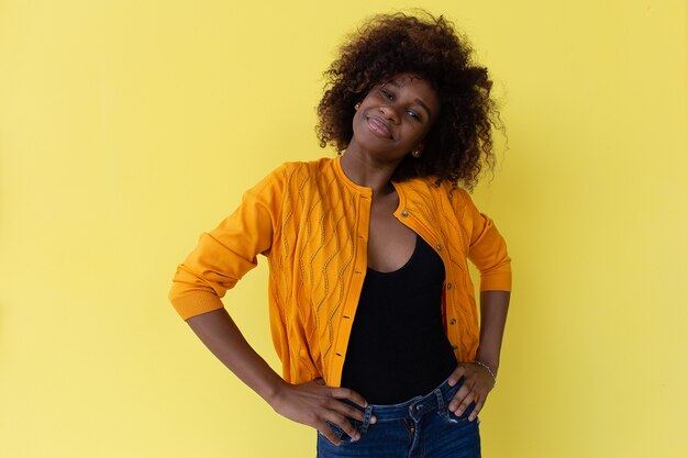 Foto a bela e feliz afro-americana em um fundo amarelo