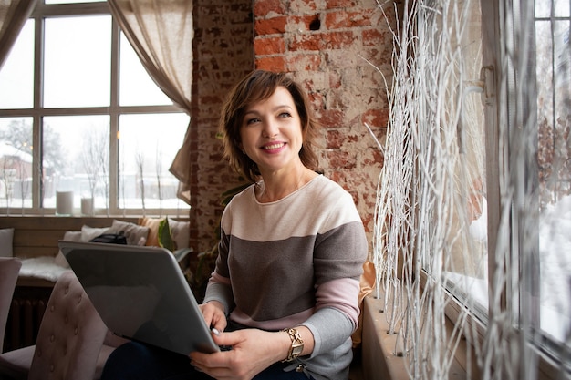 A bela mulher madura e profissional trabalha em seu laptop. mulher de negócios.