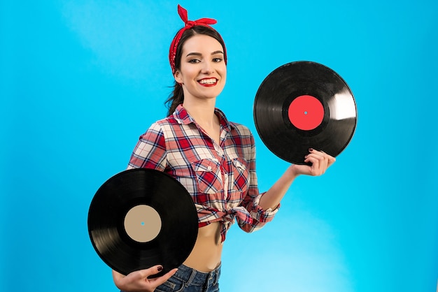 A bela mulher segurando discos de vinil no fundo azul