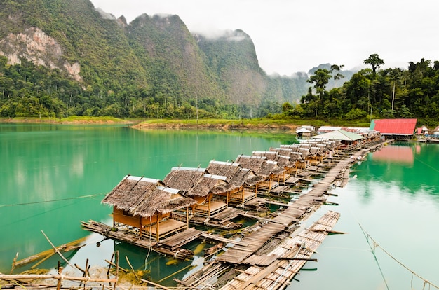 A bela paisagem natural da montanha verde e da cabana de bambu do lago flutua em uma fileira em estilo country vintage em uma manhã tranquila. viagem para a ásia no parque nacional khao sok, surat thani, tailândia