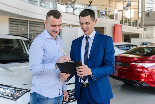 Ã Berater unterschreibt die Dokumente mit dem Käufer am Auto