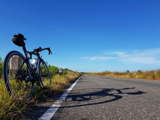 A bicicleta estacionou ao lado da estrada aberta com céu azul. Conceito de liberdade e transporte.