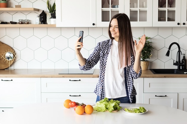 A blogueira de comida feminina faz uma transmissão ao vivo na cozinha, mostra como cozinhar alimentos saudáveis