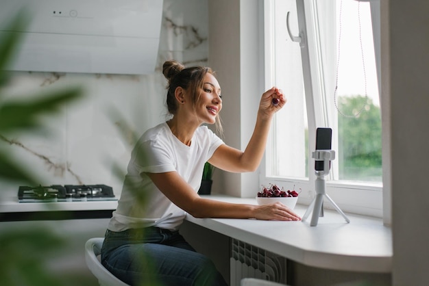 A blogueira nutricionista lidera uma transmissão ao vivo ou uma videoconferência sobre os benefícios das frutas frescas em sua cozinha em casa