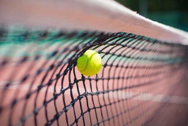 A bola de tênis bate na rede durante o jogo.