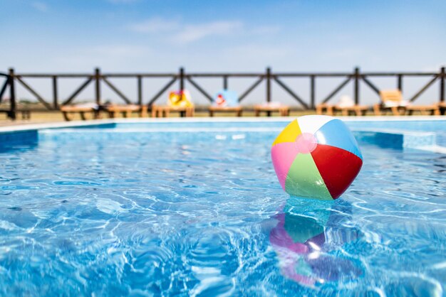 A bola flutua na superfície da água na piscina sob o sol de verão