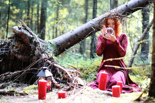 A bruxa ruiva realiza um ritual com uma bola de cristal na floresta