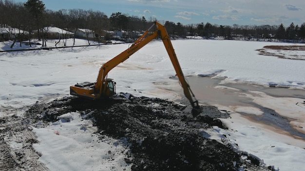 A caçamba da escavadeira de sayreville nj eua de fevereiro está mergulhada na draga de água e limpando o fundo do lago