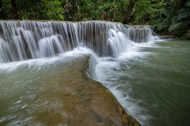 A cachoeira Hua Mea Khamin tem árvores tropicais, samambaias e crescem na cachoeira pela manhã