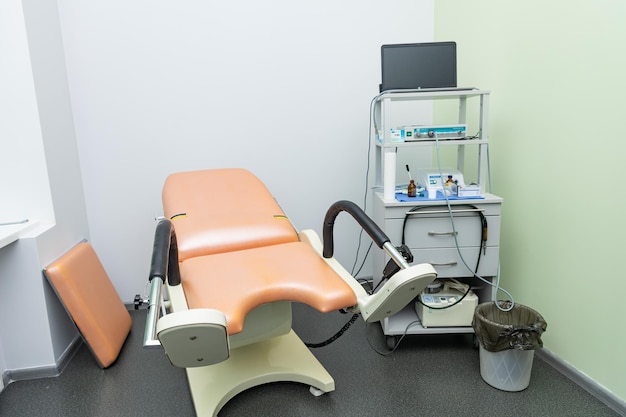 A cadeira de um paciente está em uma sala com um monitor e uma cadeira