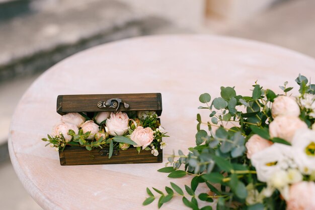 A caixa de madeira com rosas está na mesa de registro ao lado de um buquê de flores