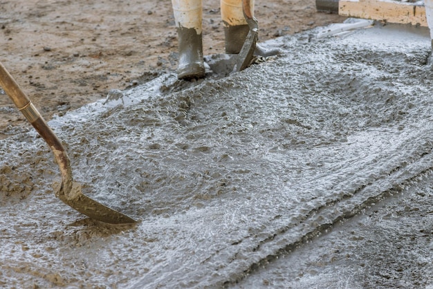 A calçada de concreto foi nivelada pelo funcionário com espátulas longas