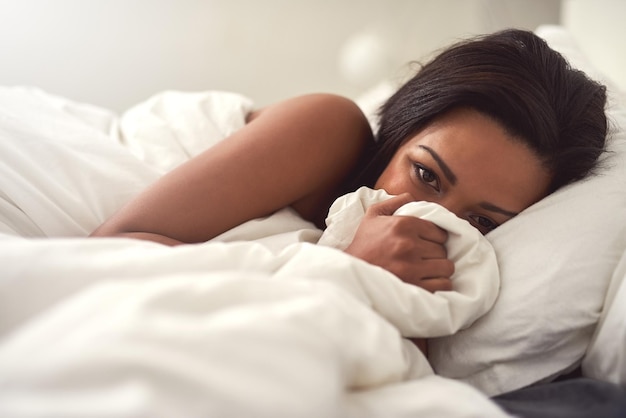 A cama é o único lugar para estar hoje Retrato de uma bela jovem deitada na cama cobrindo o rosto com lençóis