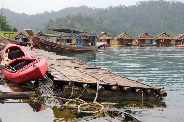 A canoa vermelha e o barco param perto O feno da cabana na balsa em Cheow Lan Dam é vintage do resto