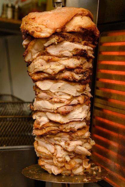 A carne de frango em uma grelha vertical é preparada para shawarma