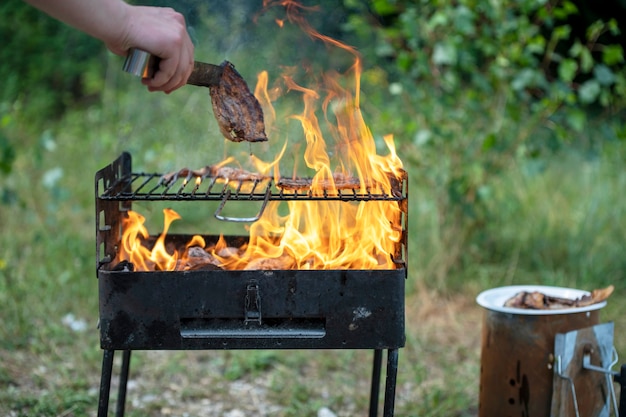 A carne é frita em uma grelha em chamas em condições de campo